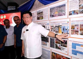 NGA Kor Ming melihat pelan cadangan menaik taraf Pasar Awam Ayer Tawar dalam lawatan kerja di Manjung, Perak, semalam. - UTUSAN/ZULFACHRI ZULKIFLI