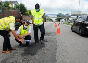 MOHD. Solihan Badri (tengah) diberi penerangan oleh Ir. Zainal Tumian (kiri) mengenai kerosakan yang berlaku pada permukaan jalan ketika melakukan lawatan bagi melihat kerja-kerja membaiki jalan di Lebuhraya Pasir Gudang-Johor Bahru, Johor. - FOTO/RAJA JAAFAR ALI