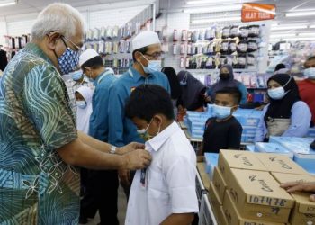 MAHDZIR Khalid membantu seorang pelajar memakai baju sekolah dalam program sumbangan pakaian sekolah anjuran Yaked di Kuala Nerang, Kedah hari ini.