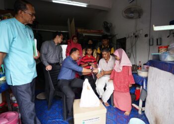 PEGAWAI Skuad Gerak Khas (SGK) MAINS, Amir Syukri Abdul Jalil (tengah) menyampaikan bantuan awal kepada Abdul Hamid yang tinggal bersama empat orang anaknya di stor di sebuah rumah kedai di Taman Tuanku Jaafar, Seremban. - IHSAN MAINS