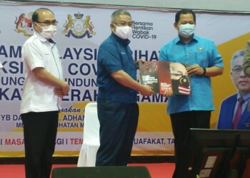 ADHAM Baba (tengah) menyampaikan buku cenderamata Covid-19 kepada Nasri Md. Ali sambil disaksikan Dr. Chong Fat Full pada Program Malaysia Prihatin, Lindungi Diri, Lindungi Semua peringkat daerah Segamat di Johor. -UTUSAN/FARAHWAHIDA AHMAD