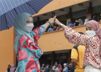 PENGUNDI muda, Nur Izzati Mohd Rasol, 26, (kiri) bersama adiknya, Nur Hanani Mohd Rasol, 22, (kanan) selesai melaksanakan tanggungjawab bagi memilih calon Parlimen Hang Tuah Jaya di Pusat Mengundi, Sekolah Kebangsaan Dato’ Demang Hussin, Bukit Katil, Melaka. - UTUSAN/RASUL AZLI SAMAD