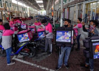 Poster pelekat calon Barisan Nasional (BN) Dewan Undangan Negeri Merlimau, Dr. Akmal Saleh ditampal pada motosikal penghantaran makanan  di pekan Merlimau, semalam.  – UTUSAN/AMIR KHALID