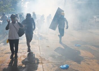 PENUNJUK perasaan melarikan diri selepas gas pemedih mata dilepaskan semasa demonstrasi menentang rampasan kuasa tentera di Yangon , Myanmar. - AFP