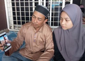 MAHASAN Mohd. Daud menunjukkan gambar anaknya, Ikmal Hakimi yang ditemukan lemas di sungai Kampung Bentong, Kluang, Johor kelmarin.