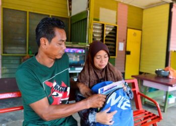 MASARI Sardi dan isteri, Liswati Ali melihat beg dan buku sekolah yang terakhir dibawa oleh anaknya sebelum mereka terjatuh dari jambatan gantung yang uzur di Kampung Rekoh, Keratong, Rompin, Pahang pada 28 April lalu. – FOTO/SHAIKH AHMAD RAZIF