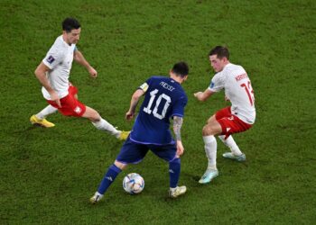 Lionel Messi dicabar dua pemain Poland dalam saingan Kumpulan C, kelmarin. - AFP