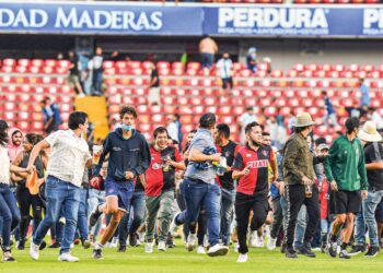 PENYOKONG Atlas dan Queretaro berlari menyelamatkan diri ke tengah padang selepas pergaduhan tercetus ketika perlawanan Liga Mexico berlangsung di Stadium Corregidora, Queretaro semalam. – AFP