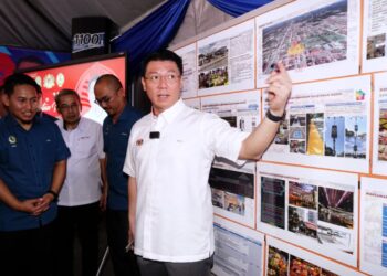 NGA Kor Ming melihat pelan pembinaan cadangan menaik taraf Pasar Awam Ayer Tawar ketika lawatan kerja di Manjung hari ini. - UTUSAN/ZULFACHRI ZULKIFLI