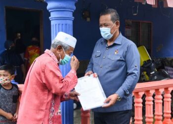 AMINUDDIN Harun menyerahkan Borang 5A kepada salah seorang penduduk Kampung Chuah di Port Dickson hari ini.