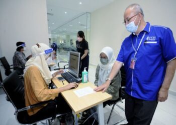 AMALUDDIN Ahmad melihat senarai kehadiran orang awam untuk mendapatkan vaksin Covid-19 dos penggalak di Hospital UCSI, Port Dickson, hari ini. - FOTO/MOHD. SHAHJEHAN MAAMIN