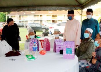 AFENDY Kamaruddin (duduk, kanan) bersama para penerima bantuan beramah mesra dengan Hazri (berdiri, dua kanan) pada Majlis Jamuan Berbuka Puasa dan Semarak Ramadan di Balai Polis Kota, Rembau, kelmarin -UTUSAN/NOR AINNA HAMZAH.