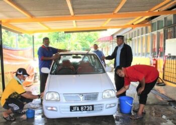 ZAINUDIN Bujang (bersongkok) memerhatikan Syed Mohd. Khairul Syed Idrus (kiri), D. Steven (dua dari kiri) dan Ariffin Jantan (berbaju merah) mencuci kereta di Pusat Jagaan Bengkel Mini Desa Rembau di Kampung Batu Hampar, Rembau. – UTUSAN/NOR AINNA HAMZAH