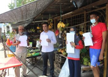 AHMAD Din (kiri) dan Mohd. Ridzuan (tengah) menunjukkan notis perobohan gerai di Sungai Layang, Rembau semalam. UTUSAN/NOR AINNA HAMZAH