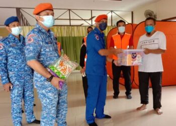 MOHD. Syukri Madnor (tengah) menyantuni seorang mangsa terjejas banjir yang menghuni PPS yang dibuka di SMK Dato' Mohd Said, Nilai, Seremban, hari ini.