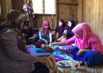 FAEZAH Hamid (kanan) menyuap makanan kepada Nor Farihan Salwani Ibrahim yang terlantar sakit kerana penyakit SLE di rumahnya di Kampung Kala, Gua Musang, Kelantan.