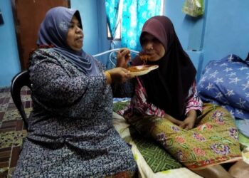 Rashidah Nanyan (kiri) setia menjaga kakaknya, Siti Eshah Nanyan, yang terlantar akibat sakit kaki ketika berada di rumah mereka di Kampung Tok Weng