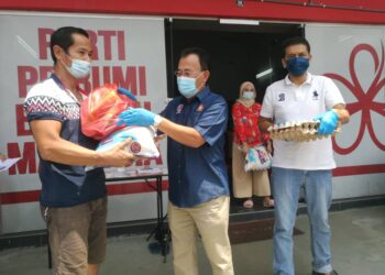 OSMAN Sapian (tengah) menyampaikan sumbangan bakul makanan kepada penerima terjejas di DUN Kempas di Johor Bahru, Johor.