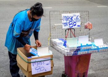 SEORANG wanita menjual pelitup muka di tepi jalan di Bangkok selepas pihak berkuasa Thailand mengenakan sekatan ketat berikutan Covid-19. - AFP