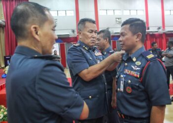 PENGARAH JBPM Perak, Azmi Osman (tengah) memakaikan pangkat kepada Shahrul Nizam Murad pada Majlis Perhimpunan Bulanan di Bandar Meru Raya di Ipoh hari ini.  -UTUSAN/MUHAMAD NAZREEN SYAH MUSTHAFA