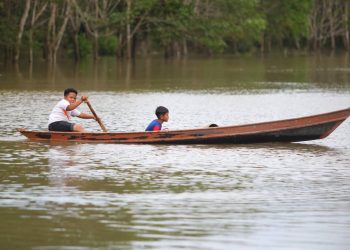 DUA kanak-kanak menaiki perahu meredah air banjir di Kampung Pak Hitam , Bakong Pasir Mas, Kelantan. - UTUSAN/ZULHANIFA SIDEK