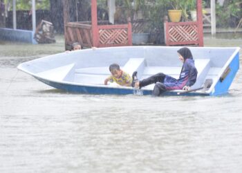 Dua  kanak-kanak di Kampung Sri Damai, Kuantan seronok bermain air di kawasan rumah mereka yang dinaiki air selepas hujan lebat berterusan sepanjang  hari semalam. - 
UTUSAN/SHAIKH AHMAD RAZIF