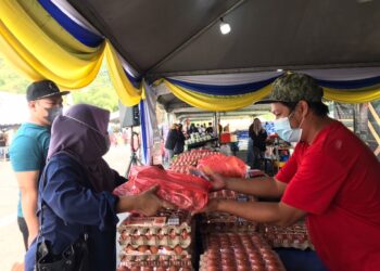 ADNAN Azizi Zainal Abidin (kanan) menjual telur ayam kepada pengunjung pada PJKM di RTC Gopeng hari ini. - UTUSAN/LIYANA RAMLI