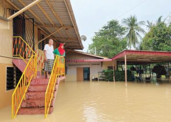 AHMAD OMAR dan isterinya, Ramlah Zakaria hanya mampu termenung di tangga rumah apabila rumah mereka dinaiki air di Jelempok, Arau, Perlis hari ini.- UTUSAN/MOHD. HAFIZ ABD. MUTALIB