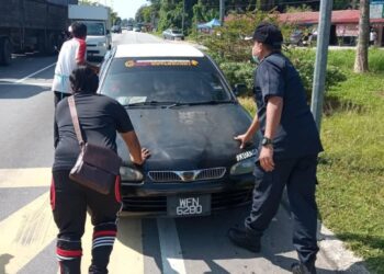 ANGGOTA polis membantu wanita dan bayi lelakinya berusia empat bulan selepas kereta mereka mengalami kerosakan di persimpangan Bota Kanan dekat Parit hari ini. - IHSAN BALAI POLIS BOTA