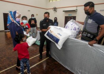 WAN Kamarul Azran Wan Yusof (kiri) menyerahkan sumbangan kepada anggota polis yang terjejas akibat banjir di Ibu Pejabat Polis Daerah Sepang, Selangor. - UTUSAN/FAISOL MUSTAFA