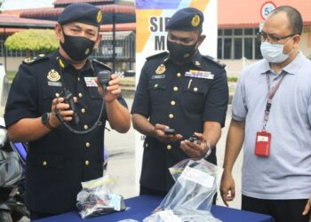 ADENAN Mat Isa (kiri) menunjukkan peralatan komunikasi yang dipercayai tidak dilesenkan yang digunakan oleh tonto-tonto untuk memantau pergerakan anggota JPJ dalam sidang akhbar selepas operasi di sekitar Butterworth, Pulau Pinang hari ini. UTUSAN/MOHAMMAD FIRDAUS AMRAN