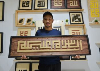 MUHAMMAD Hanis bersama antara tulisan khat kufi yang dihasilkannya di Terengganu. -UTUSAN/PUQTRA HAIRRY