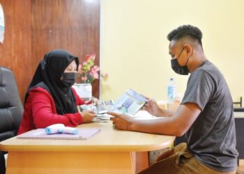 SUZIANA Mohammad menerangkan kepada seorang pelanggan pakej-pakej pelancongan 
yang ditawarkan agensi pelancongannya, Sunny Travel di Jeti Kuala Besut, Besut, 
Terengganu. – UTUSAN/PUQTRA HAIRRY ROSLI