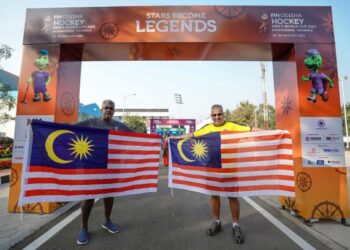 ARIA Duray (kiri) dan Raj Veer Singh mengibar Jalur Gemilang ketika hadir menonton perlawanan Malaysia menentang Sepanyol pada saingan crossover, Piala Dunia 2023 di Bhubaneswar, India, Ahad lalu. - UTUSAN/FARIZ RUSADIO