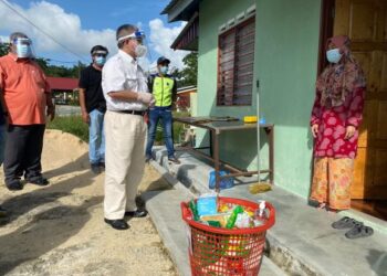 ADHAM Baba (tengah) menyalurkan bantuan makanan kepada penduduk Kampung Lukut, Kota Tinggi, Johor, baru-baru ini.