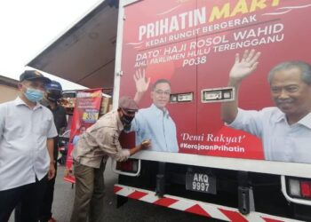 ROSOL Wahid (kanan) menurunkan tandatangan pada bahagian belakang kedai runcit bergerak, Prihatin Mart di Dataran Padang Kacung, Kuala Telemong, Hulu Terengganu hari ini. - FOTO/NOOR HAYATI MAMAT