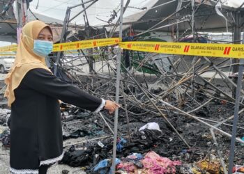 HANISAH Abu Bakar menunjukkan pakaian kanak-kanak yang musnah selepas khemah jualannya di Bazar Syawal Pekan Rabu, Kuah, Langkawi, Kedah, terbakar, hari ini. - UTUSAN/ NUR AMALINA AZMAN