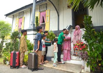 KEGEMBIRAAN jelas terpancar pada wajah Hajratun Bibi Mohd. Ali, 73, ketika menyambut kepulangan anak, menantu serta cucunya di Kampung Lama Arau, Perlis, semalam. - UTUSAN/IZLIZAN OTHMAN