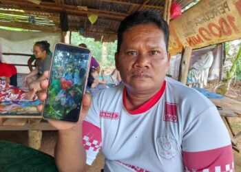 SHARIMAN menunjukkan gambar adiknya, T. Norihan yang cedera parah ditembak penyeludup di sempadan Malaysia-Thailand ketika ditemui di Perkampungan Orang Asli Ibam di Bera, Pahang. - FOTO/SALEHUDIN MAT RASAD