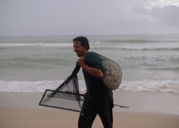 SEORANG penduduk bersama hasil siput laut yang berjaya dikutip di Pantai Rusila berdekatan Kampung Rhu Dua di Marang, Terengganuhari ini. - UTUSAN/PUTRA HAIRY ROSLI