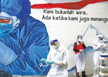 Petugas kesihatan bersiap sedia menjalankan ujian saringan Covid-19 secara pandu lalu di Klinik Ajwa Seksyen 7, Shah Alam, Selangor, berlatar belakangkan mural lukisan penghargaan buat barisan hadapan memerangi pandemik berkenaan. -GAMBAR HIASAN/UTUSAN