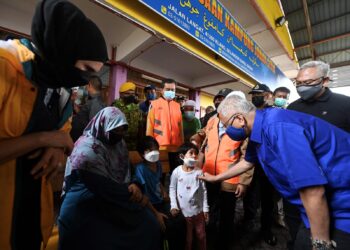 Datuk Seri Ismail Sabri Yaakob (kanan) menyantuni kanak-kanak ketika melawat mangsa banjir di Pusat Pemindahan Sementara (PPS) di Sekolah Kebangsaan Telok Gong pada 19 Disember 2021. -FOTO/JABATAN PERDANA MENTERI