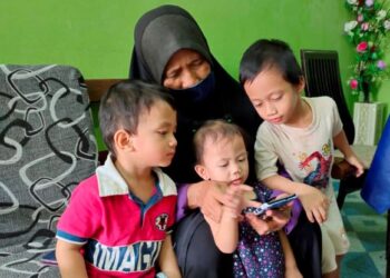 HUSNUL Fatimah Mustofa (tengah) menunjukkan gambar arwah Nurul Chasanah Ahmad Sobirin kepada tiga cucunya di Kampung Delek, Klang, Selangor, semalam. - UTUSAN/ISKANDAR SHAH MOHAMED