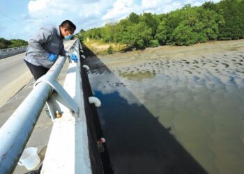 KAKITANGAN sebuah makmal bebas menggunakan peralatan khas, Van Dorn water sampler ketika mengambil sampel air Sungai Kim Kim pada Mac lalu. – FOTO/RAJA JAAFAR ALI