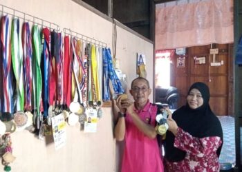 MASHAYIKH Subari bersama isterinya, Badariah Jamal menunjukkan sebahagian pingat yang pernah dimenangi pemanah negara, Syaqiera yang kini beraksi di Sukan Olimpik ketika ditemui di Felda Medoi, Segamat di Johor. -UTUSAN/FARAHWAHIDA AHMAD