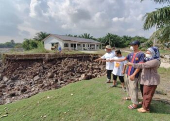 AIDI Ahmad Soriani (kiri), Norhalidah Mohammed Khalim (kanan) dan Muhammad Farid Aidi Ahmad (dua dari kanan) menunjukkan mendapan tanah tidak jauh dari rumah mereka akibat banjir serta arus deras di Kampung Sepakat Jaya, Kampung Lombong di Kuala Langat, Selangor.