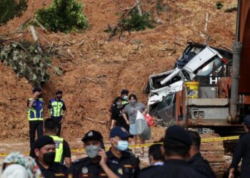 BEBERAPA orang penduduk membawa beg berisi barangan keperluan yang diambil dari rumah mereka yang terjejas akibat tanah runtuh di Taman Bukit Permai, Ampang yang berlaku lewat petang Khamis. - FOTO/MUHAMAD IQBAL ROSLI