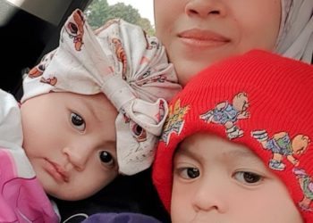 SITI Nurul Asikin Noryadi memangku dua anaknya, Asfa Danish Norazmi  (kanan) dan Asfa Darissa selepas 10 bulan terpisah ketika wanita itu bekerja di Singapura.