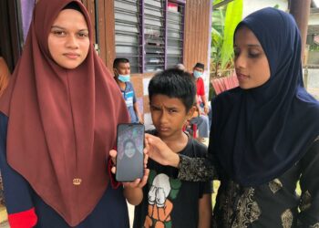 NUR Albaniah Harun (kiri) menunjukkan gambar Halizam Hamzah yang disimpan di dalam telefon bimbitnya di Yong Peng, Batu Pahat, Johor, semalam.