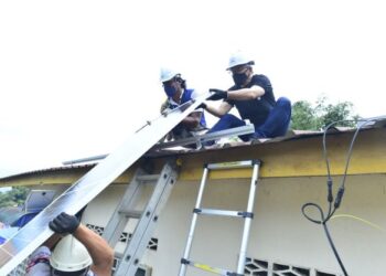 TI Lian Ker (atas bumbung, kanan) membantu memasang panel solar di Kampung Orang Asli Bukit Telaga di Raub, Pahang. - FOTO/SHAIKH AHMAD RAZIF